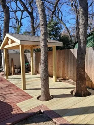 Composite and wood deck with pergola frame around large trees, clear sunny day