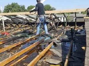 Roof decking removal showing exposed wood beams and structural framing repair work