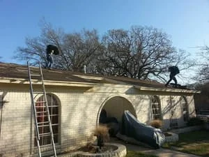 Brick home with new asphalt shingle roof installation and ladder setup