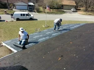 Crew installing asphalt shingles on residential roof with underlayment and fasteners